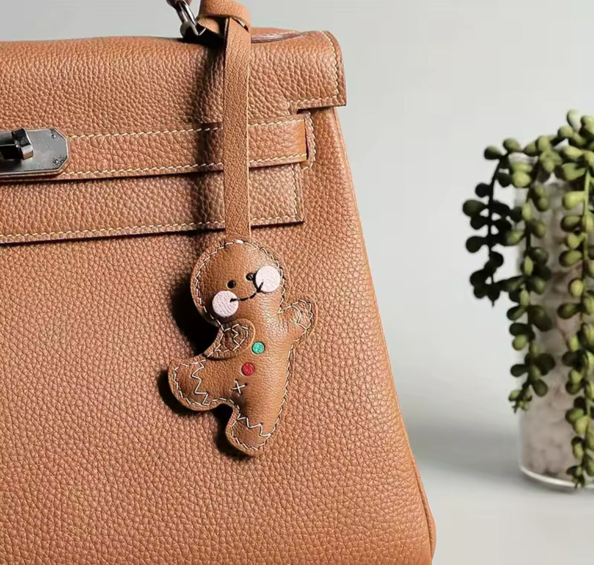 Charm en cuir façon bonhomme pain d’épices suspendu à un sac.