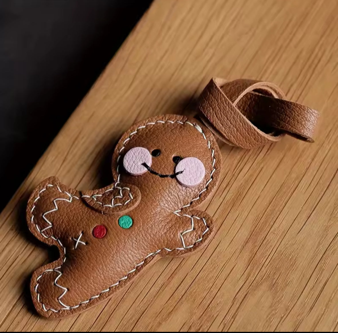 Figurine pain d’épices en simili cuir avec détails brodés, tenue en main.