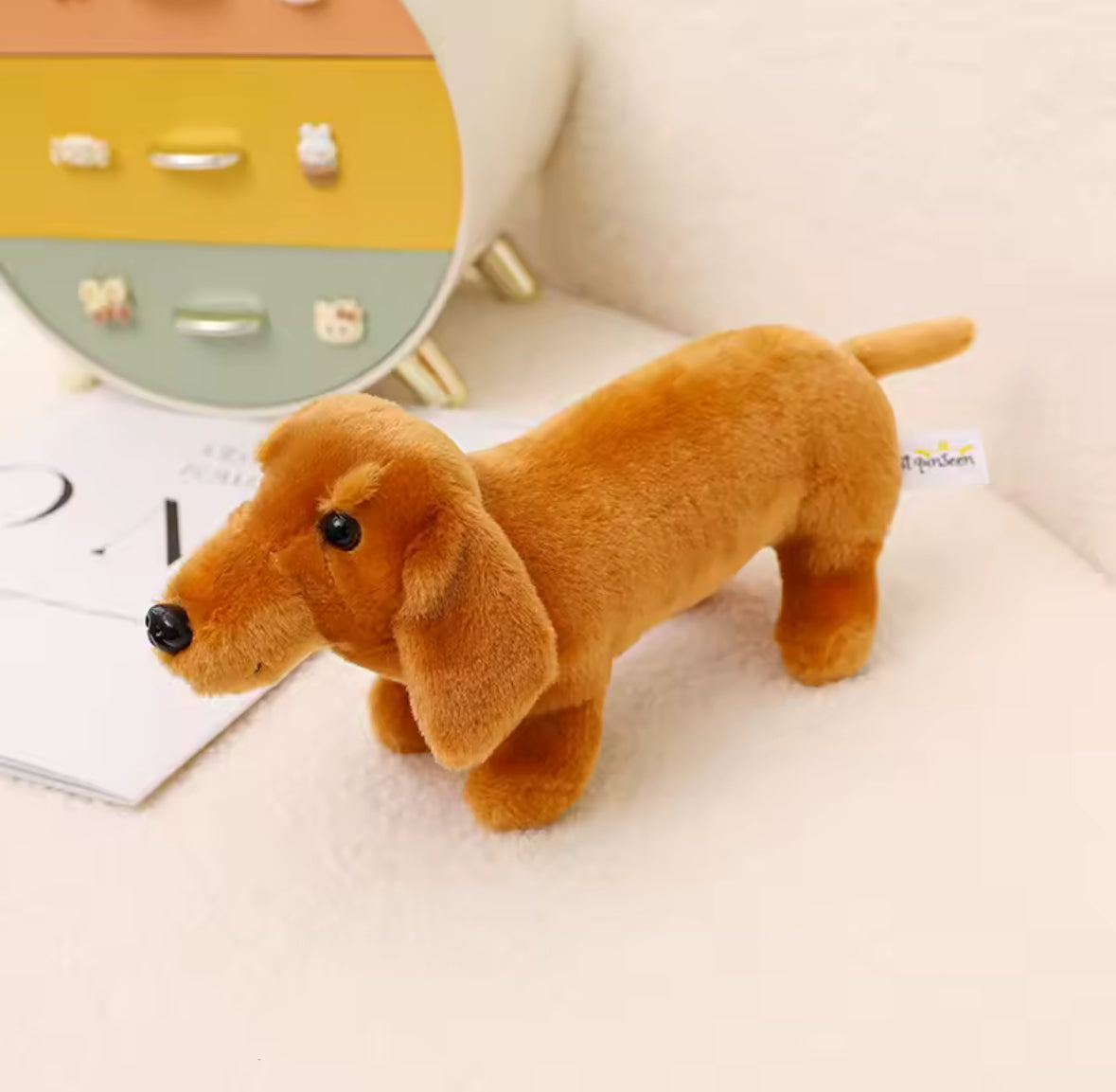 Jouet en peluche chien saucisse, silhouette longue et pattes courtes.