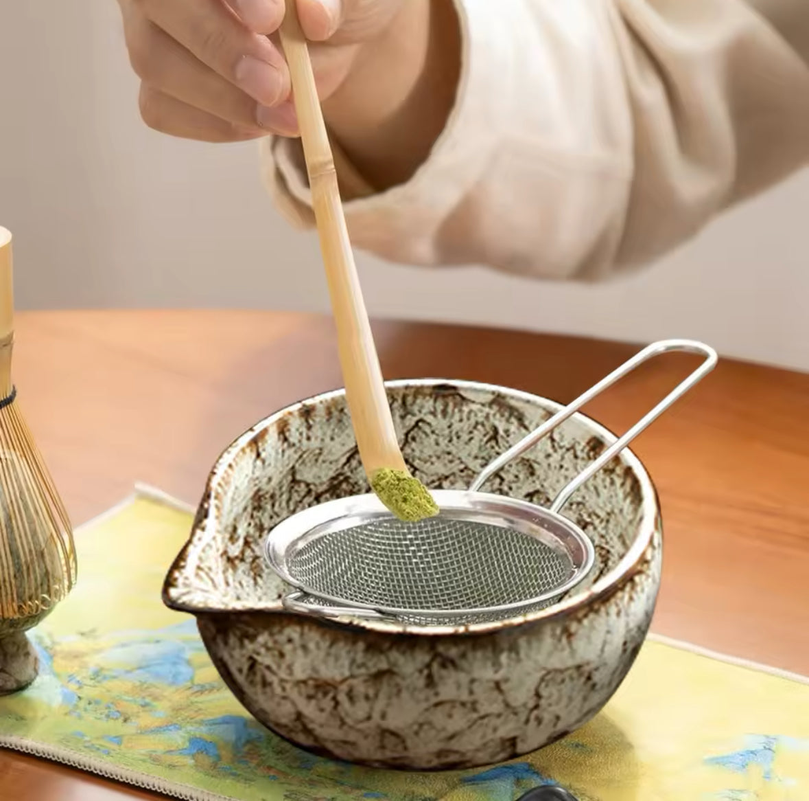 Préparation du thé matcha avec bol artisanal et tamis en acier inoxydable