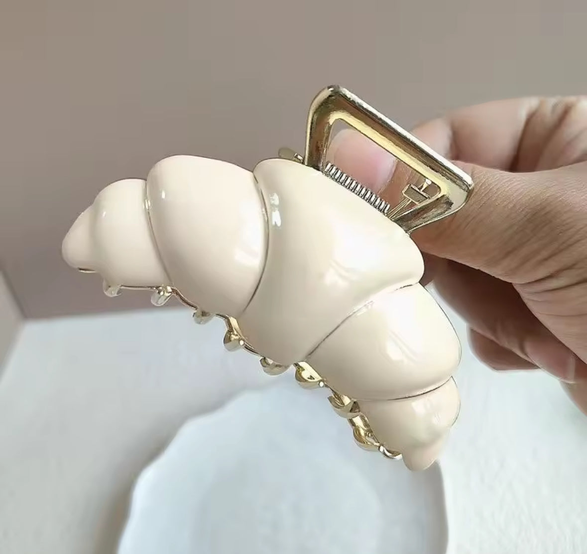Pince croissant beige crème posée sur fond neutre