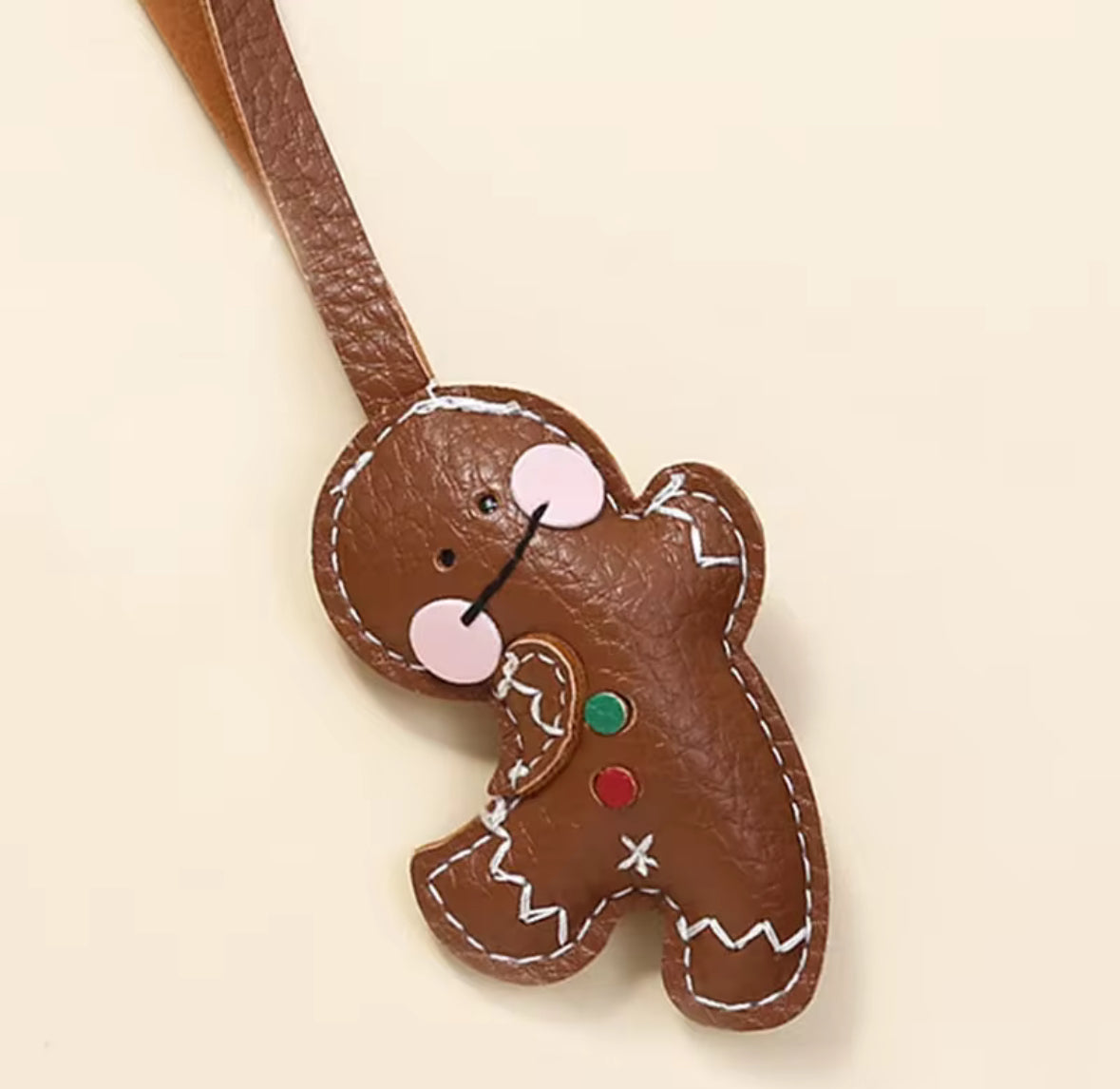 Décoration miniature gingerbread en cuir synthétique posée sur une surface claire.