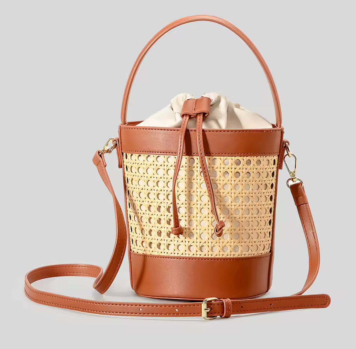 Sac seau en rotin artisanal avec bandoulière en cuir, idéal pour un style bohème chic.