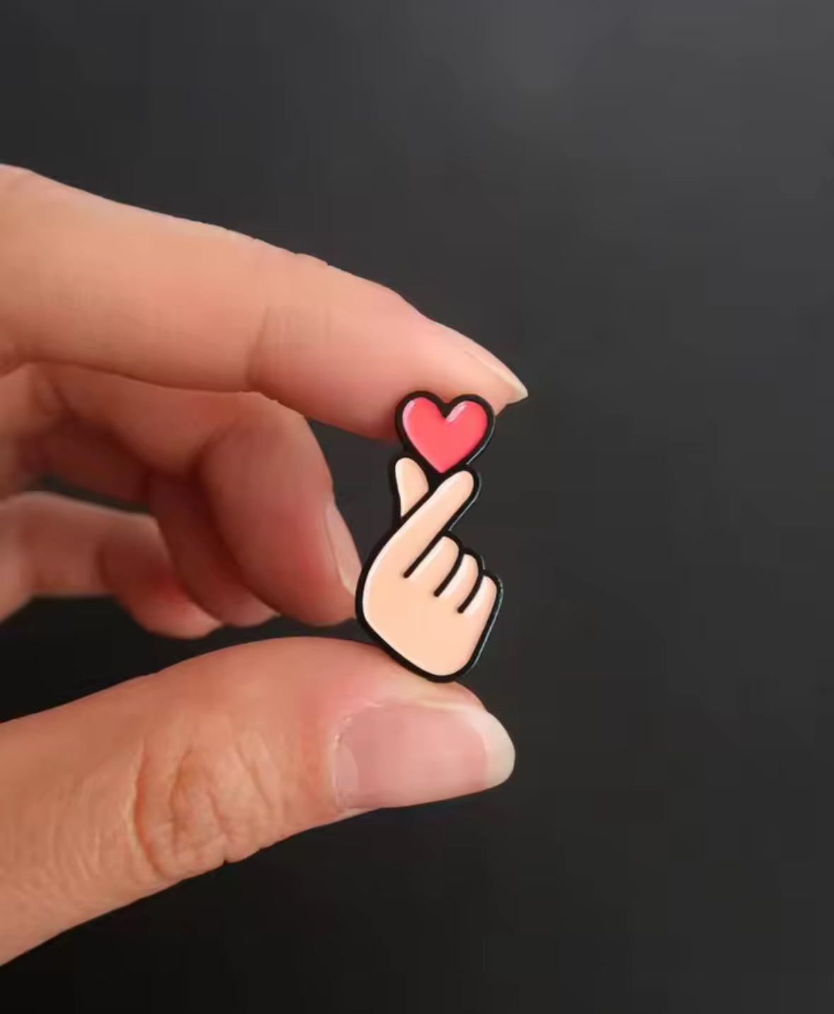 Geste Finger Heart en pin’s noir et or, bijou coréen pop culture pour un look tendance